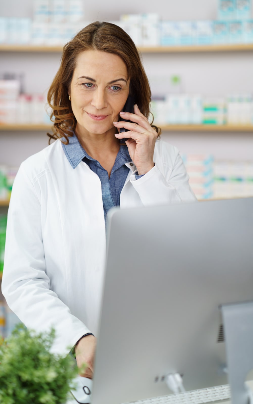 Foto/Grafik Quelle: shutterstock.com [419838433 Schöne Frau im mittleren Alter, die von hinter ihrem Schreibtisch aus telefonische Bestellungen mit einem großen Monitor vor ihrer Frau entgegennimmt © stockfour] 